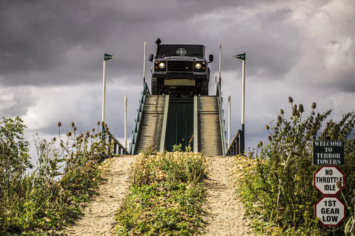 Land Rover at the top of a high ramp about to come down onto the off-road track