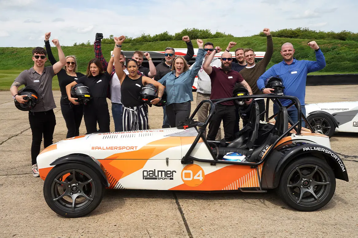 Corporate team fist pumping the air behind a Caterham