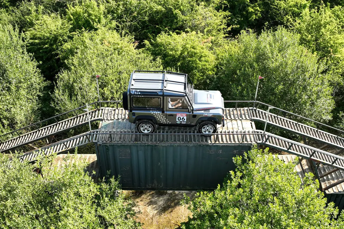 Land Rover on top of ramp within forest